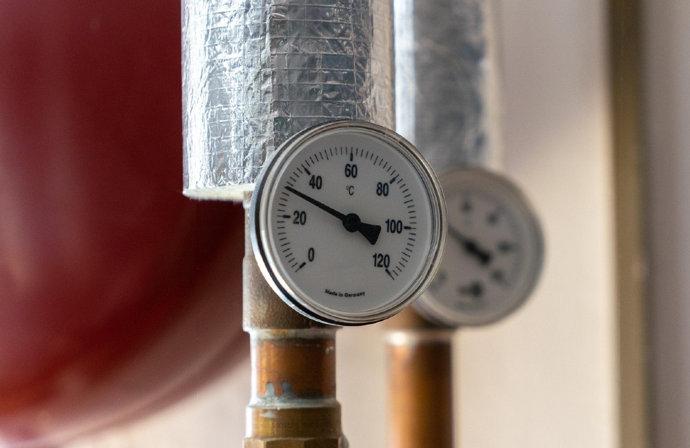 Isoliertes Heizungsrohr mit Temperaturanzeige, die rund 60 °C anzeigt – Symbolbild für Wärmeverluste in Heizungsrohrleitungen.