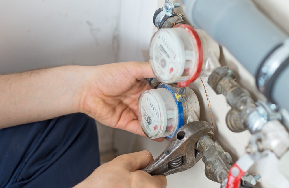Handwerker tauscht Wasserzähler mit roter und blauer Markierung aus – Symbolbild für turnusmäßigen Zähleraustausch alle fünf Jahre.